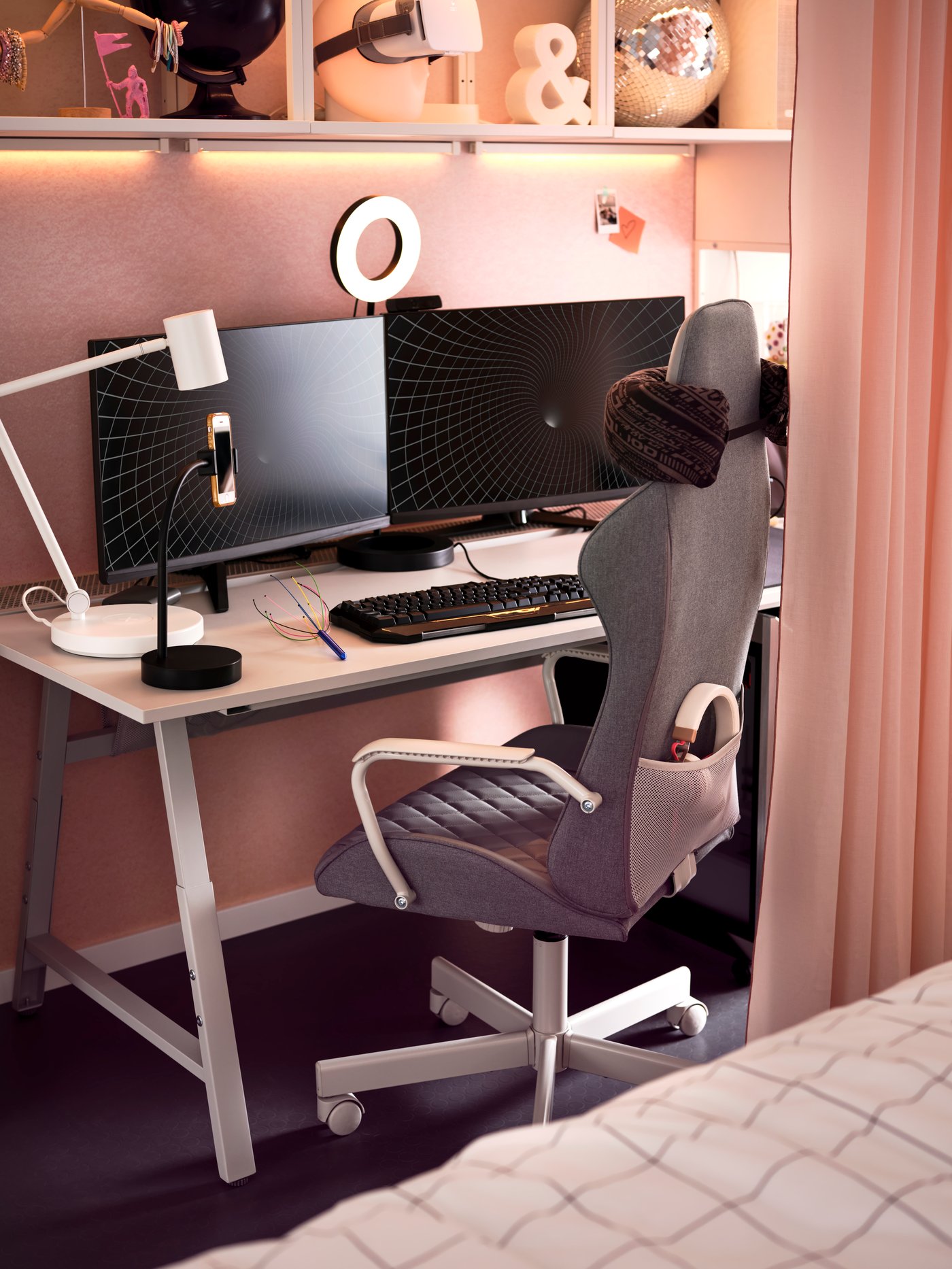 A dark grey UTESPELARE chair in front of a light grey desk holding two monitors, two desk lamps, a ring light and keyboard.