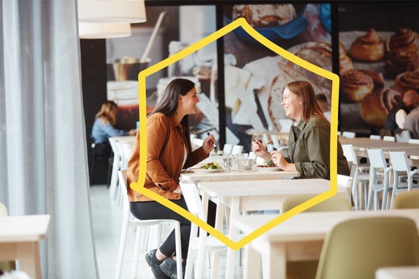 Zwei lächelnde Frauen sitzen sich in einem Schwedischen Restaurant gegenüber und essen.