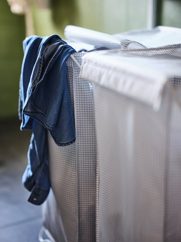 A half full PURRPINGLA laundry bag standing on the floor next to a brown wooden table.