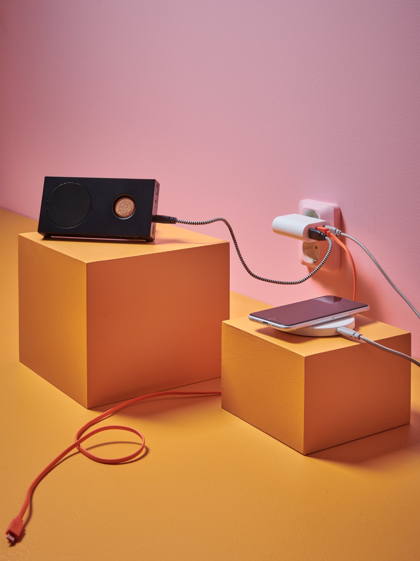 ENEBY bluetooth speaker standing on a yellow cube and LIVBOJ wireless charger on another yellow cube.