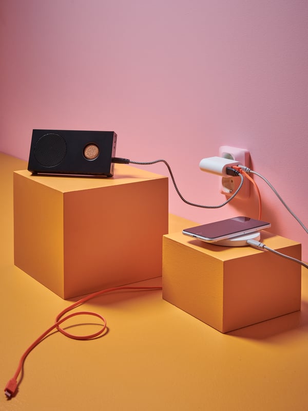Enceinte Bluetooth ENEBY sur un cube jaune et chargeur sans fil LIVBOJ sur un autre cube jaune.