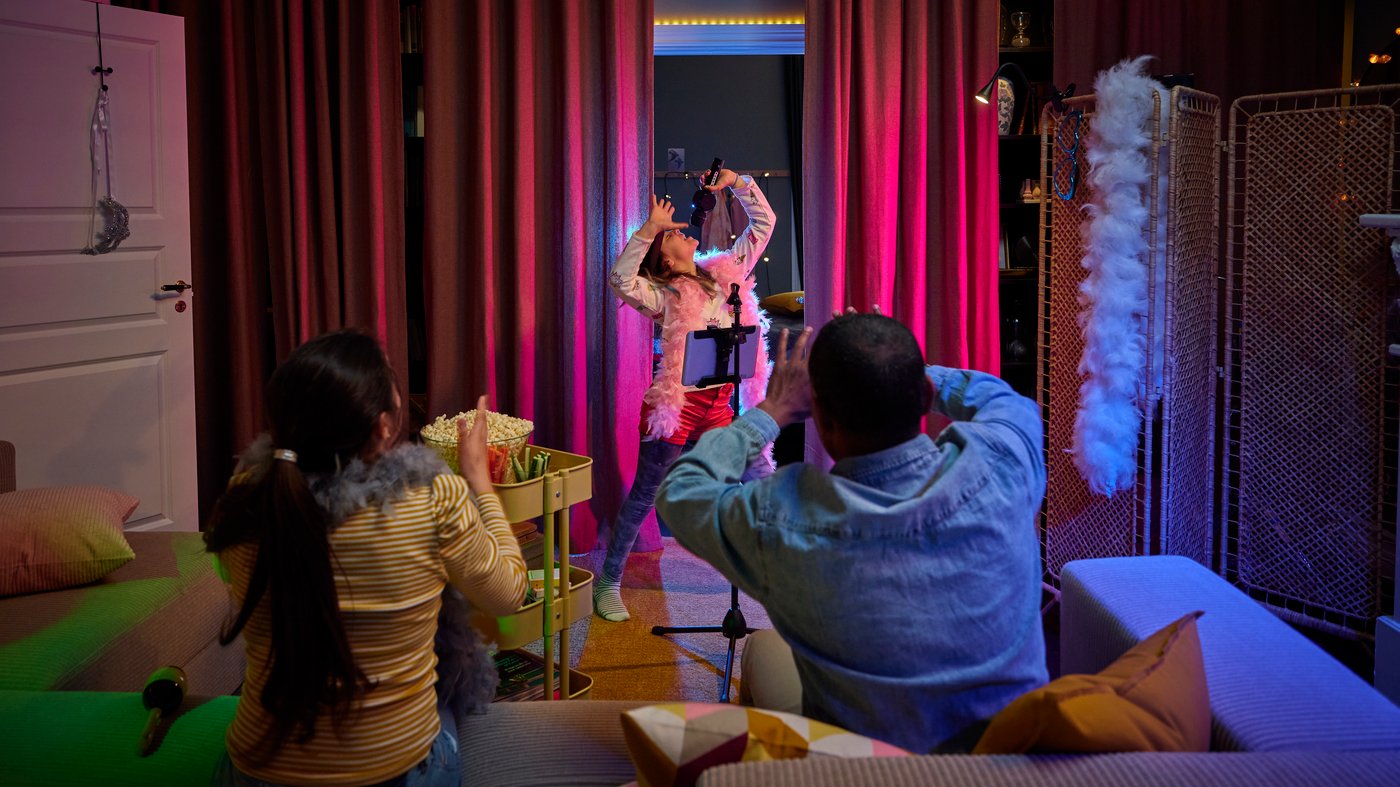 A child is performing a show for her father and sister.