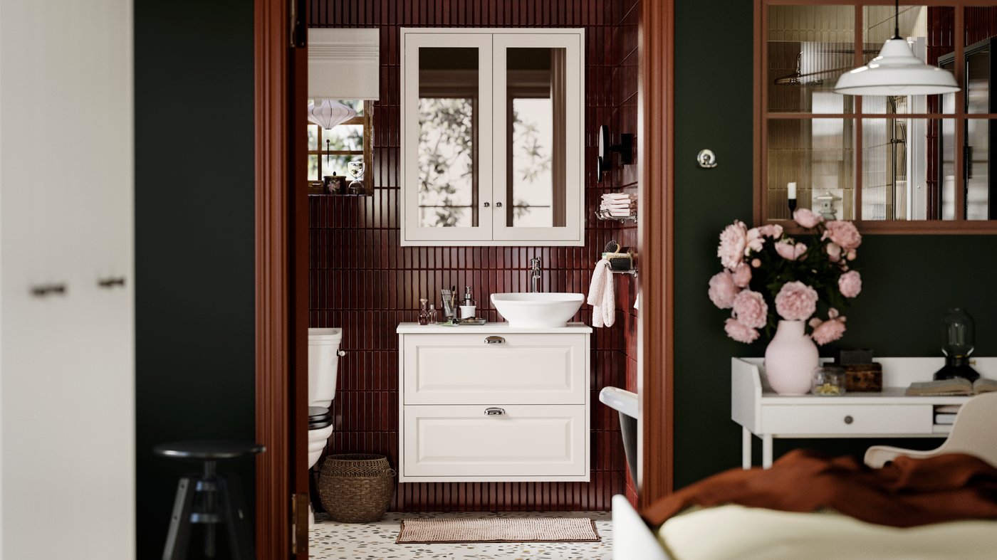 A contemporary bathroom with terrazzo floors, featuring a TÄNNFORSEN wash-stand and a dark maroon tile wall.