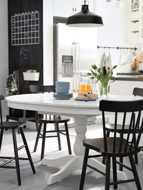 INGATORP white round table and four black chairs standing in a white kitchen, a black pendant lamp hangs above.