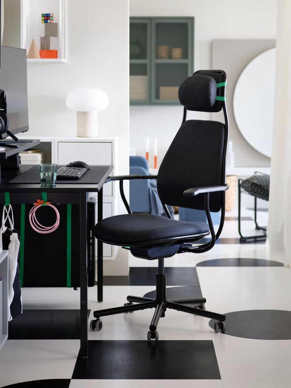 A dark grey LÖPARBANA gaming chair with a removable headrest faces a matching UTVISNING gaming desk on a passageway wall.