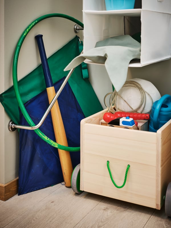 An angled VOXNAN towel rail storing a hula hoop and kite beside a FLISAT toy storage with wheels and hanging RASSLA storage.