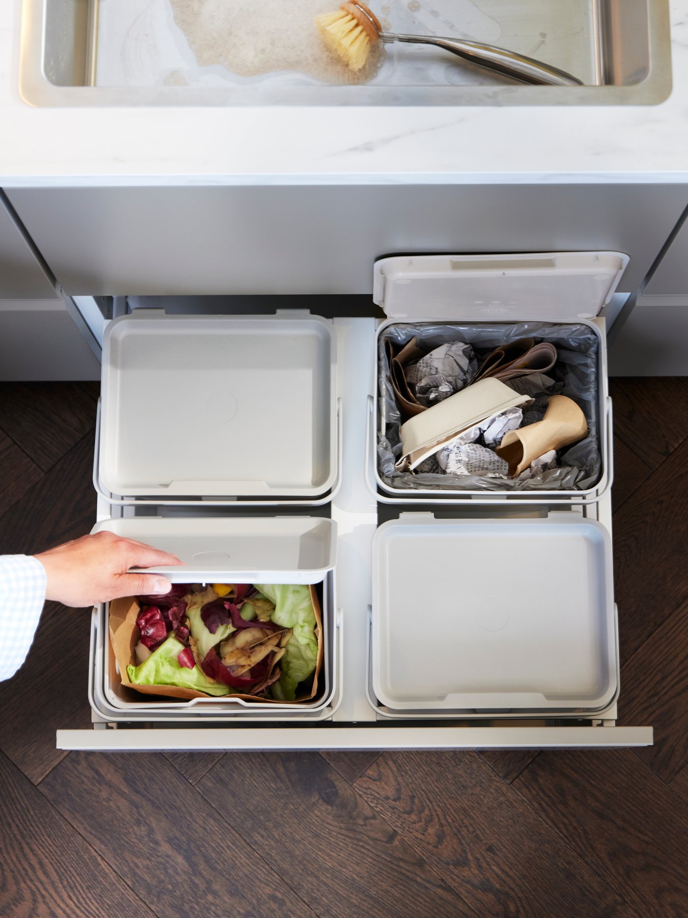 Integrated rubbish and recycling bins in a pull out drawer of a modern white IKEA kitchen