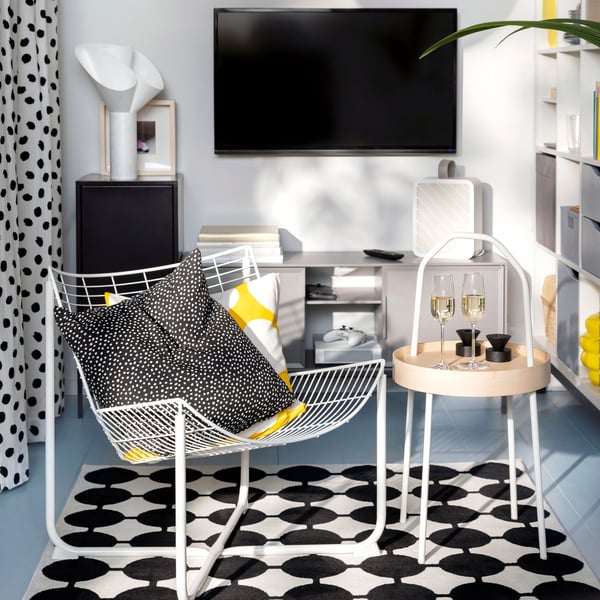 Fauteuil SKÅLBODA blanc et table d’appoint BURVIK sur un tapis VÄNDPLATS noir et blanc dans un petit espace séjour.