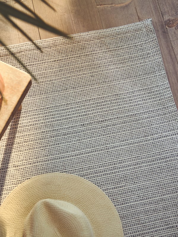 Two HAVSTA coffee tables sit on a rug with a GRÖNLID sofa, two pouffes and two rattan armchairs at the edges of the rug.