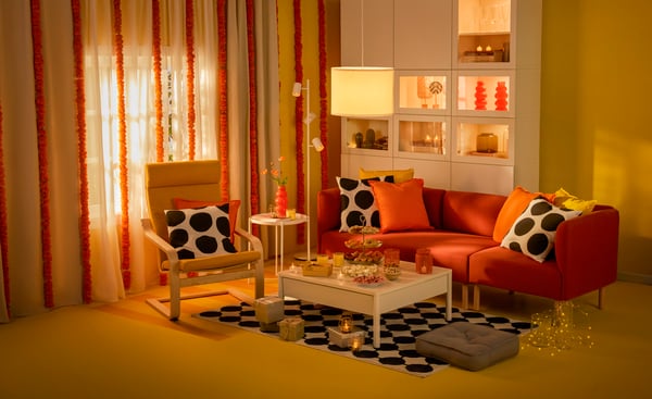 A white/black/dot pattern BLÅMUNKAR cushion cover, white TONSTAD coffee table, yellow POANG armchair and red LILLEHEM sofa in the living room as part of Deepavali celebrations