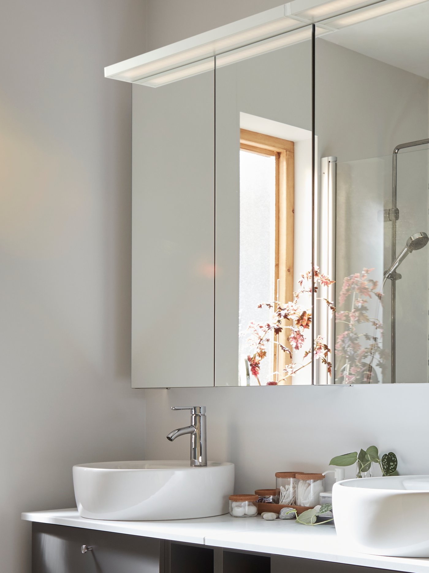 Two wash basins side by side. Mirrored cabinets with GODMORGON LED cabinet lights at the top are in front of them.