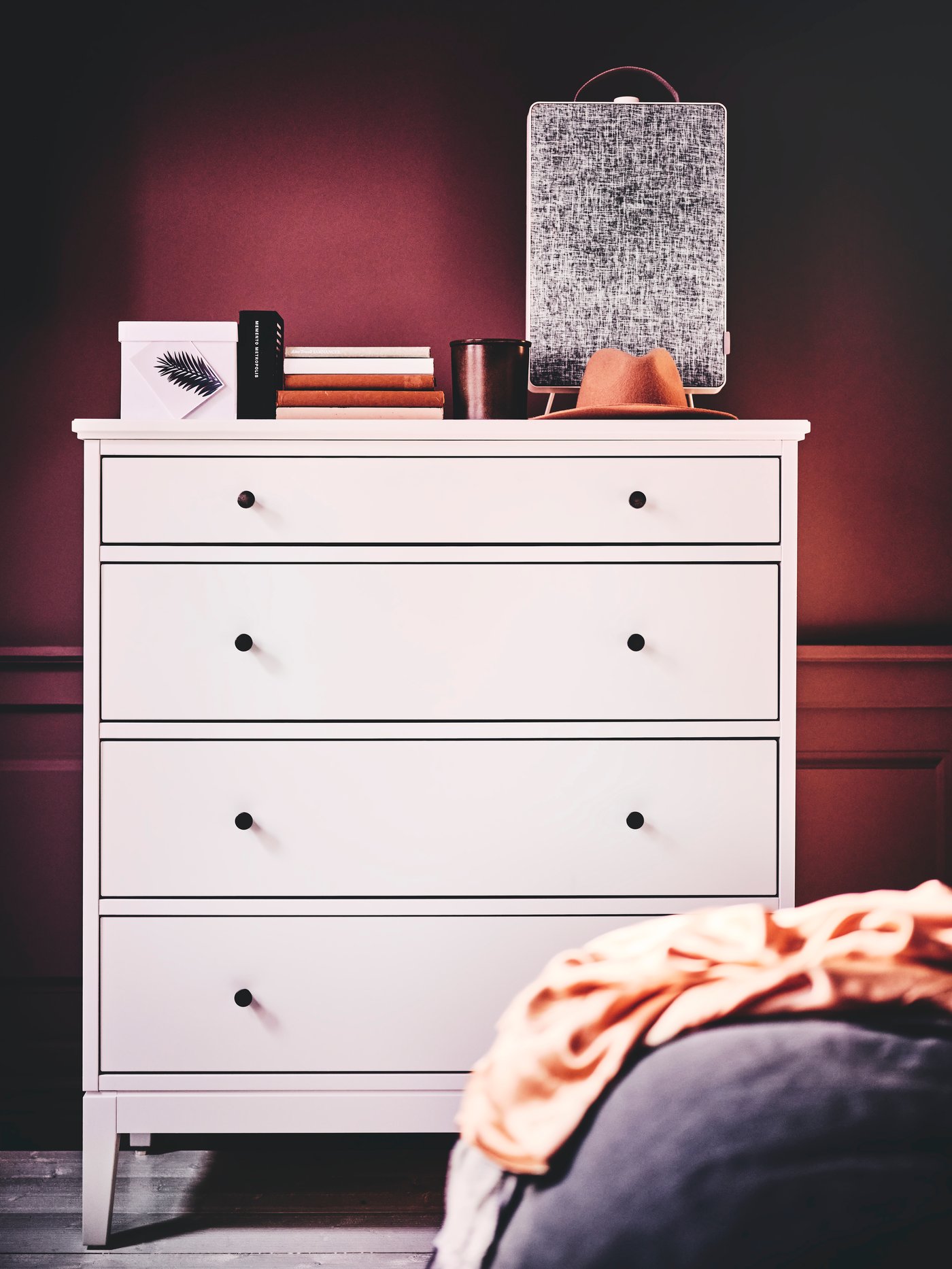 Una cómoda blanca de madera IDANÄS de cuatro cajones en la pared de un dormitorio.