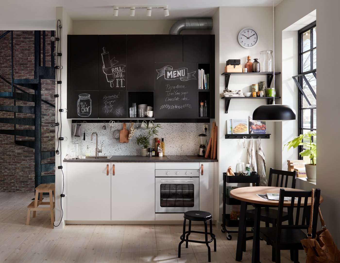 A small kitchen corner with white cabinets at the bottom and chalk doors inscribed with messages above.