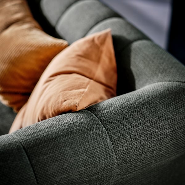Tepi atas panel fabrik bagi penjuru sofa dua tempat duduk VISKAFORS berwarna kelabu-hijau. Dua kusyen berada di atas sofa.