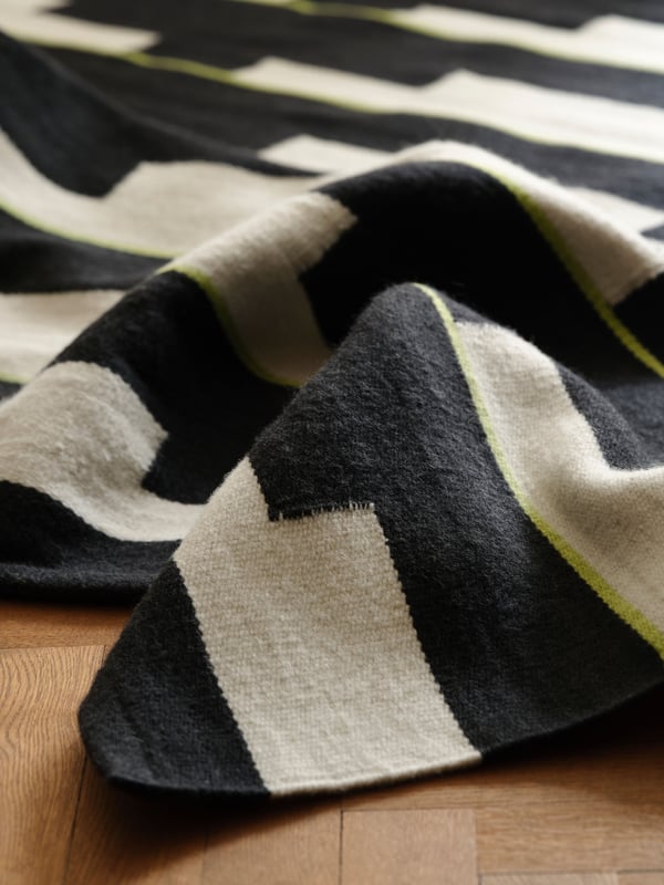 A black/white/light green handwoven STOCKHOLM 2025 rug, flatwoven