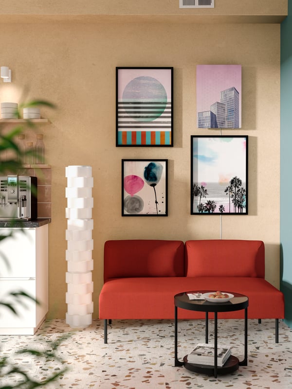 Crvena LILLEHEM modularna sofa s dva sedišta bez rukohvata nalazi se pored svetloroze zida s modernim uramljenim printovima i zvučnikom.