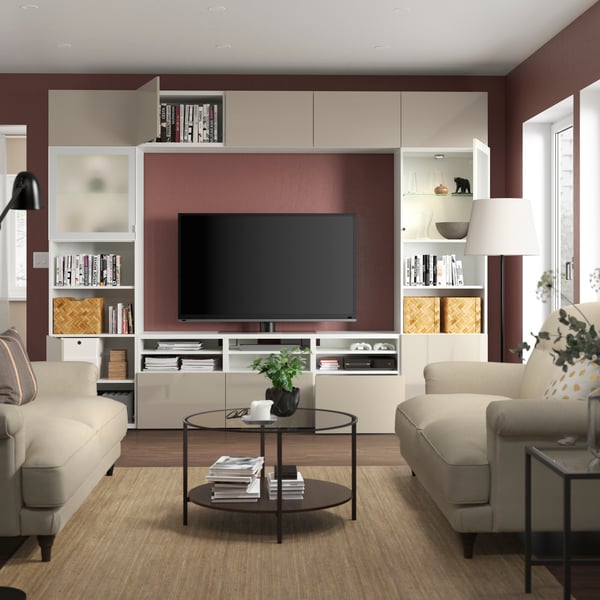 Eine BESTÅ TV-Kombination in Weiß/Selsviken-Hochglanz/beigem Milchglas mit Glastüren im Wohnzimmer