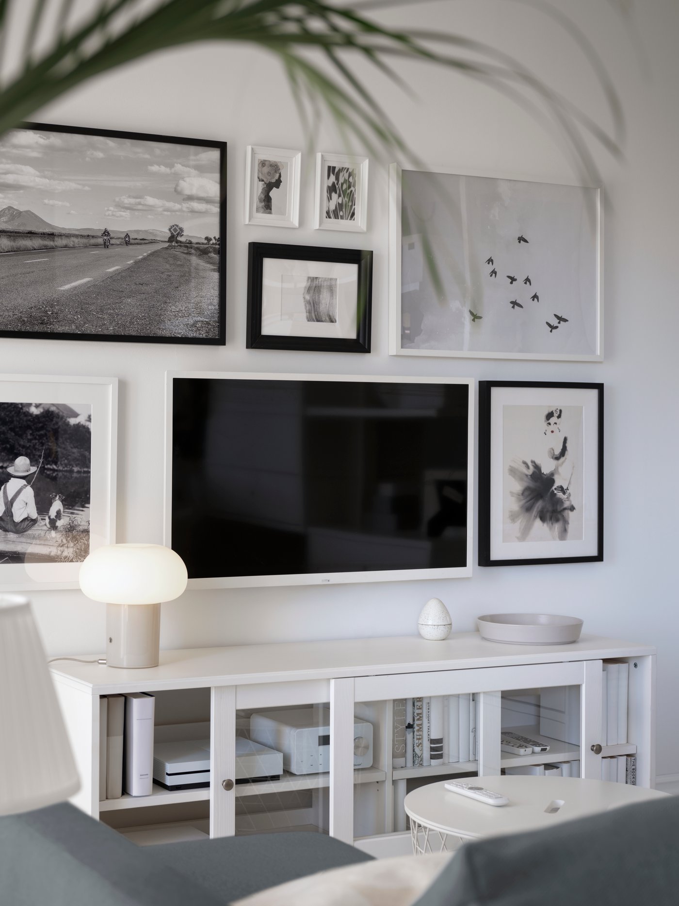 Un rack HAVSTA con puertas de vidrio y un televisor anclado en la pared sobre el mueble.