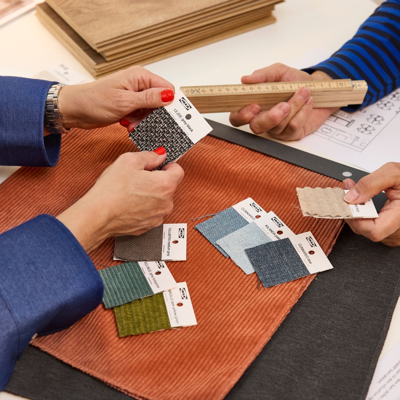 En indretningsarkitekt fra IKEA viser en kunde forskellige tekstilprøver til et interiørprojekt.