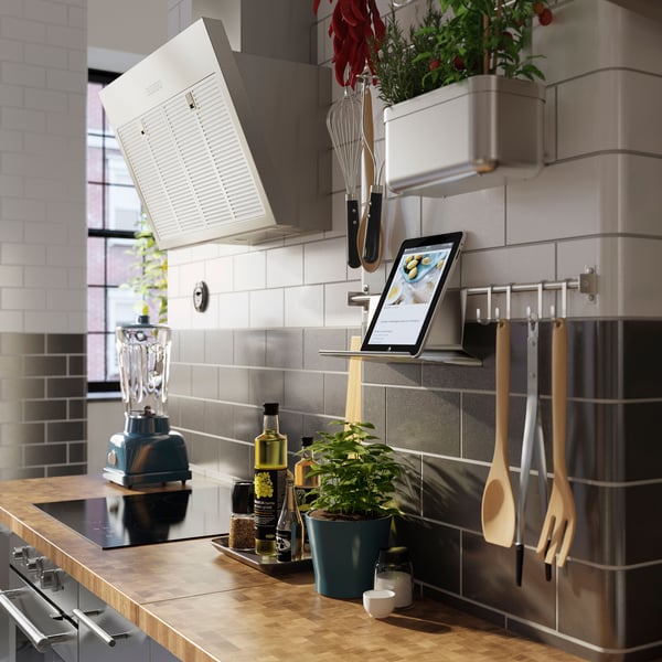 A grey and white tiled kitchen wall has a SKOGSÅ white oak worktop by an induction hob.