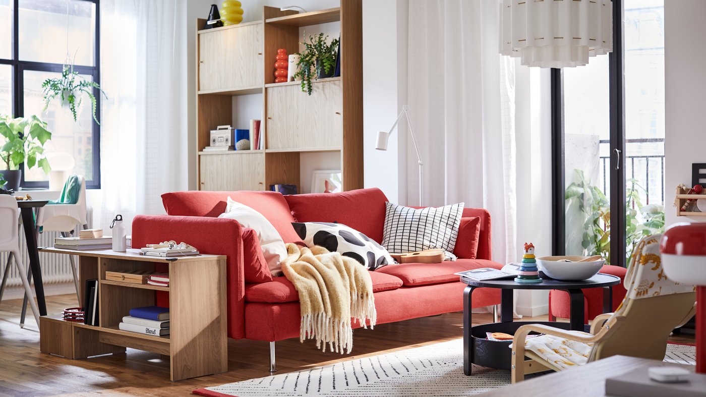 A red SÖDERHAMN sofa and a HOLMERUD side table stand in a living room in front of a LÅDMAKARE storage combination.