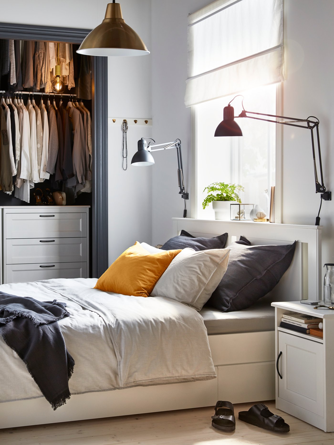 A bedroom with an open closet and a SONGESAND white bed frame with four storage boxes, grey bedding and a white nightstand.