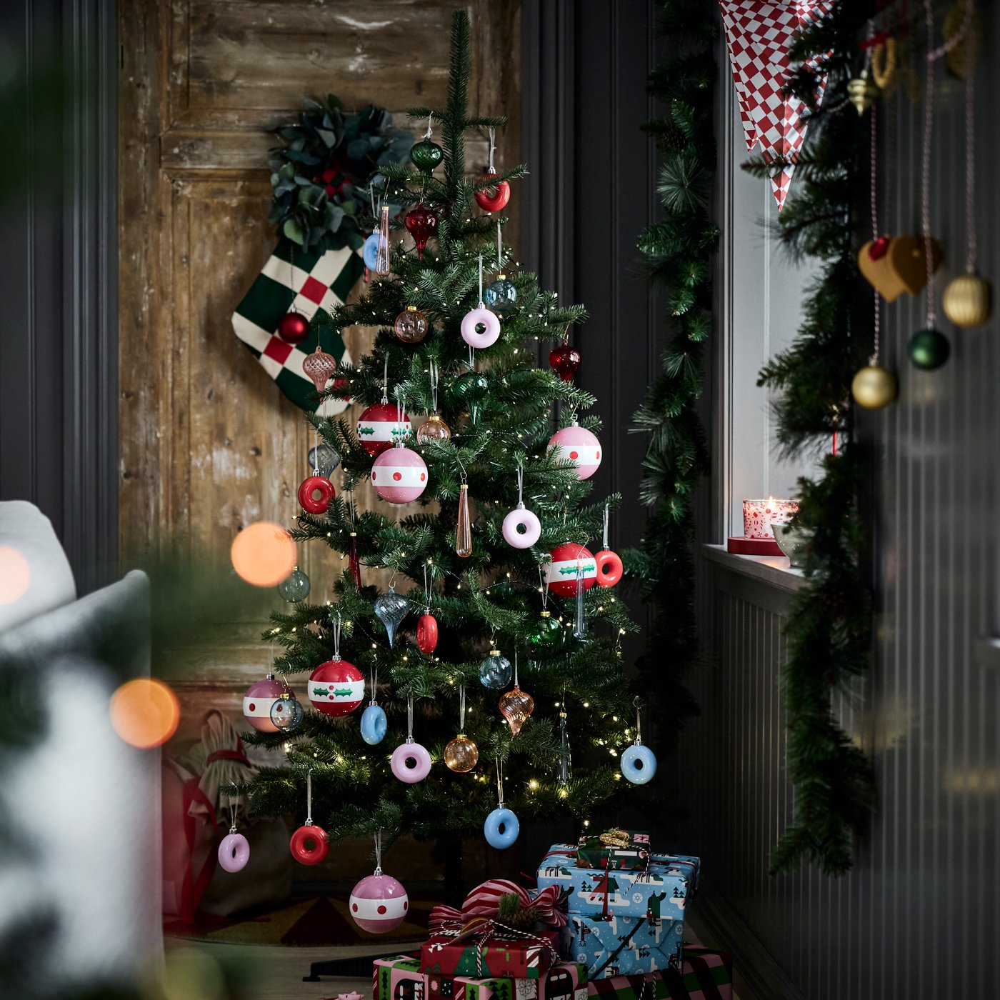 A Christmas tree is decorated with playful VINTERFINT tree ornaments shaped like donuts hanging on its branches.