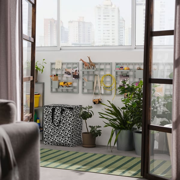 Vista a un balcón desde el interior de un apartamento. En las paredes del balcón hay tableros SNICKRA con juguetes infantiles en repisas.