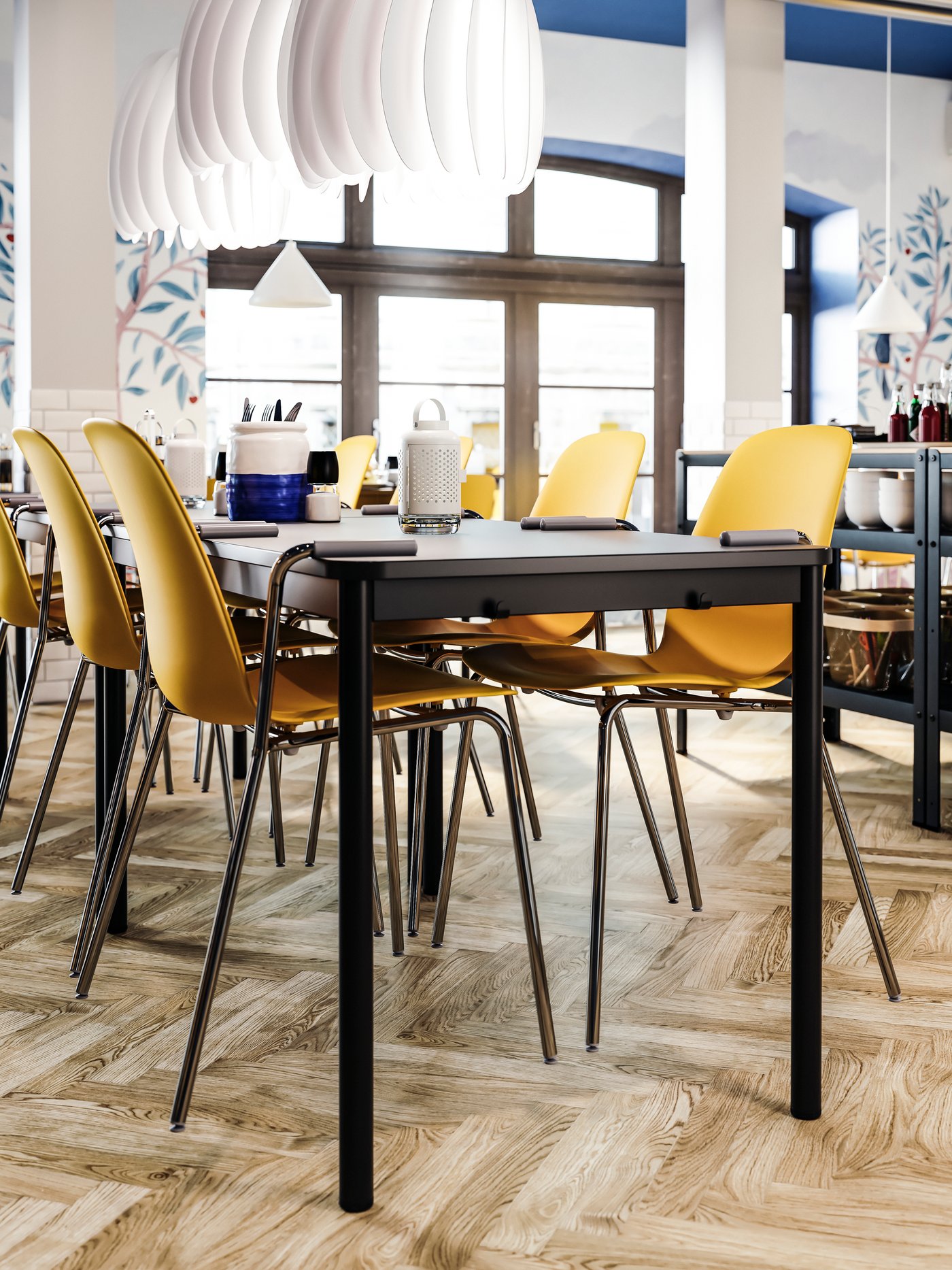 Dark yellow chairs with armrests hanging on an anthracite table, wooden floors, white pendant lamps.