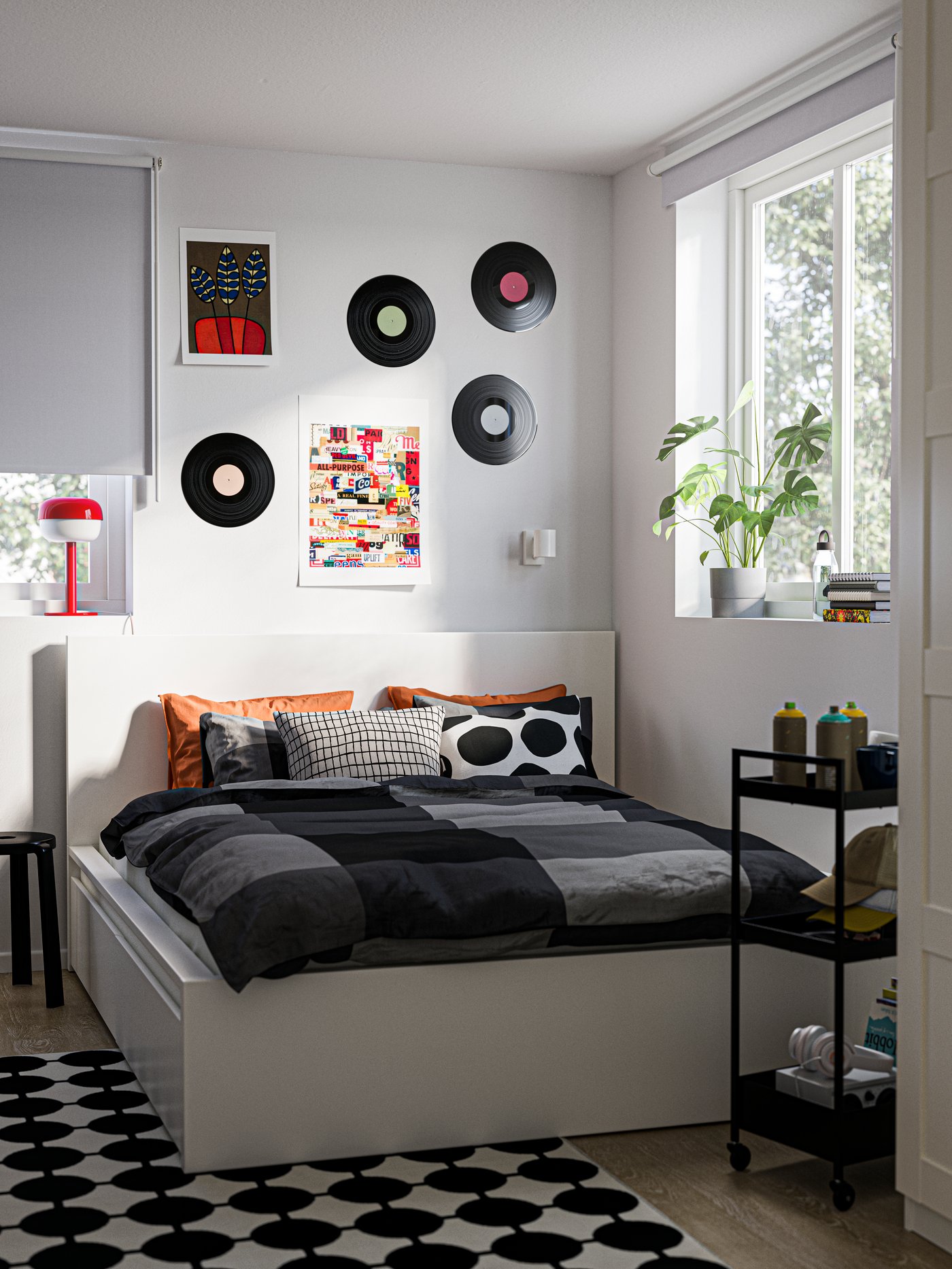 Eine Ecke im Schlafzimmer mit einem MALM Bett, einem schwarz-weißen Teppich VÄNDPLATS auf dem Boden und alten Schallplatten an der Wand über dem Bett.