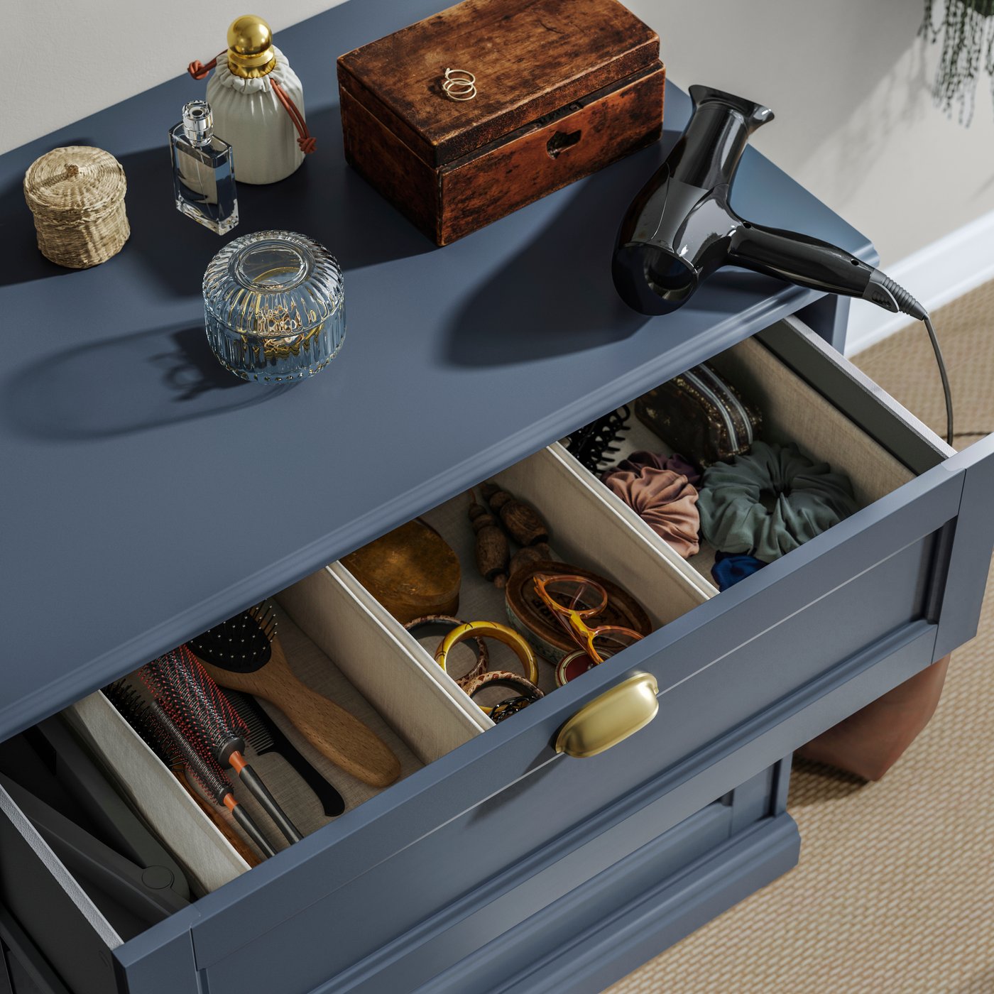 A close-up of a dark grey-blue FÅGELFJÄLLET chest of 3 drawers with items on top and an open drawer full of hair accessories.