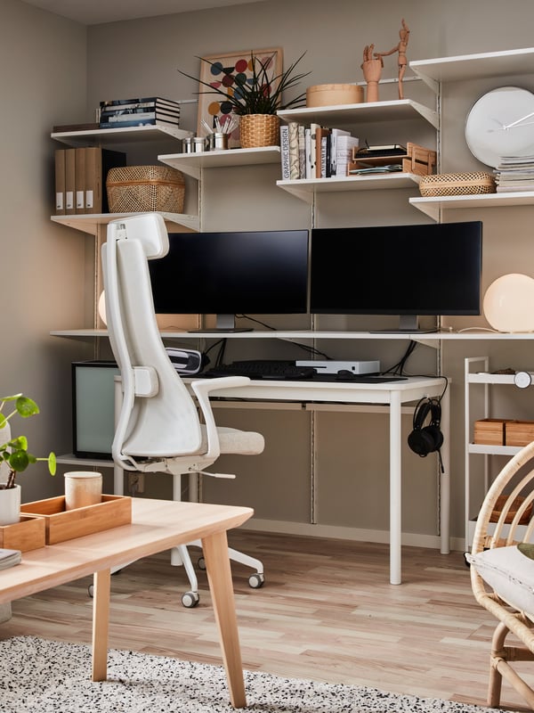 Un escritorio gamer con dos monitores encima en el costado de un living.