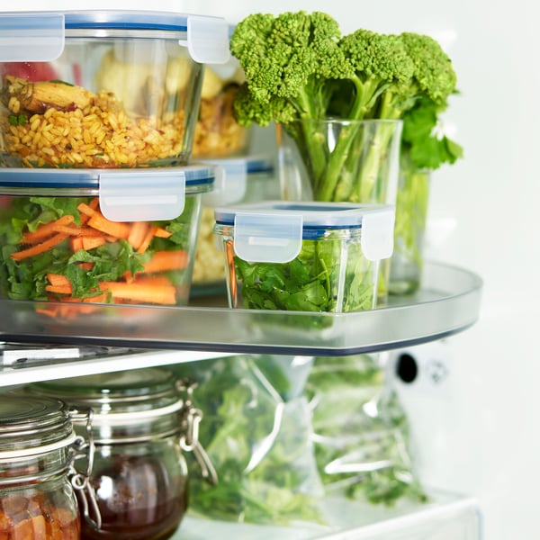 Organiserad kylhylla med matlådor, ris, grönsaker, broccoli i glas samt burkar och påsar med olika livsmedel.