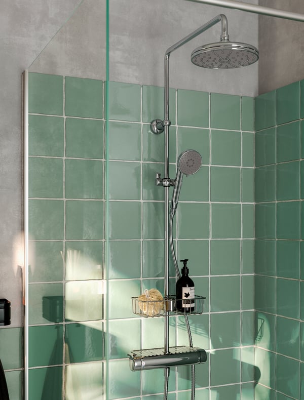 Blick auf eine grün gehaltene Dusche mit modernen Badarmaturen.