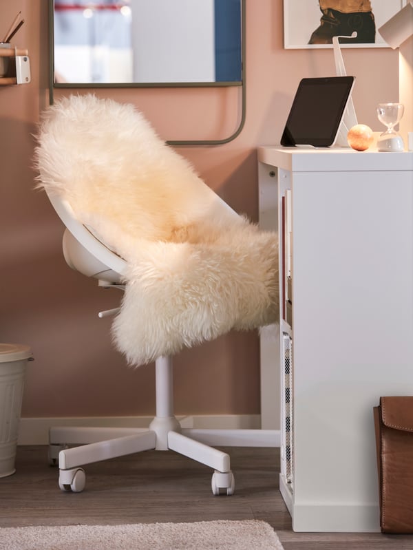 A small home office with a white LOBERGET/MALSKÄR swivel chair covered with an ULLERSLEV sheepskin by a white KALLAX desk.