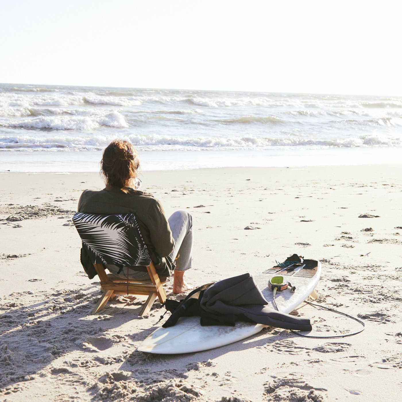 Someone sitting by the ocean on KÅSEBERGA beach chair with a backrest featuring a black and white palm-inspired print.