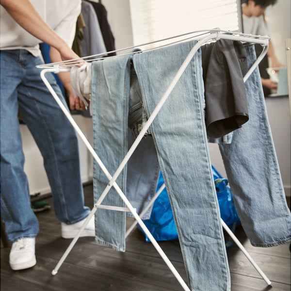 Clothes hanging on a drying rack to air out between wears instead of being washed.