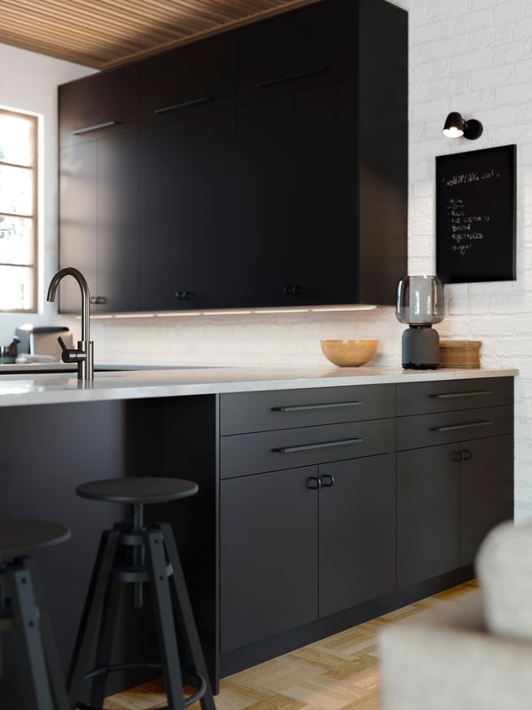 A kitchen with NICKEBO drawers and door fronts in matte anthracite and a SYMFONISK glass shaded speaker lamp with Wi-Fi.