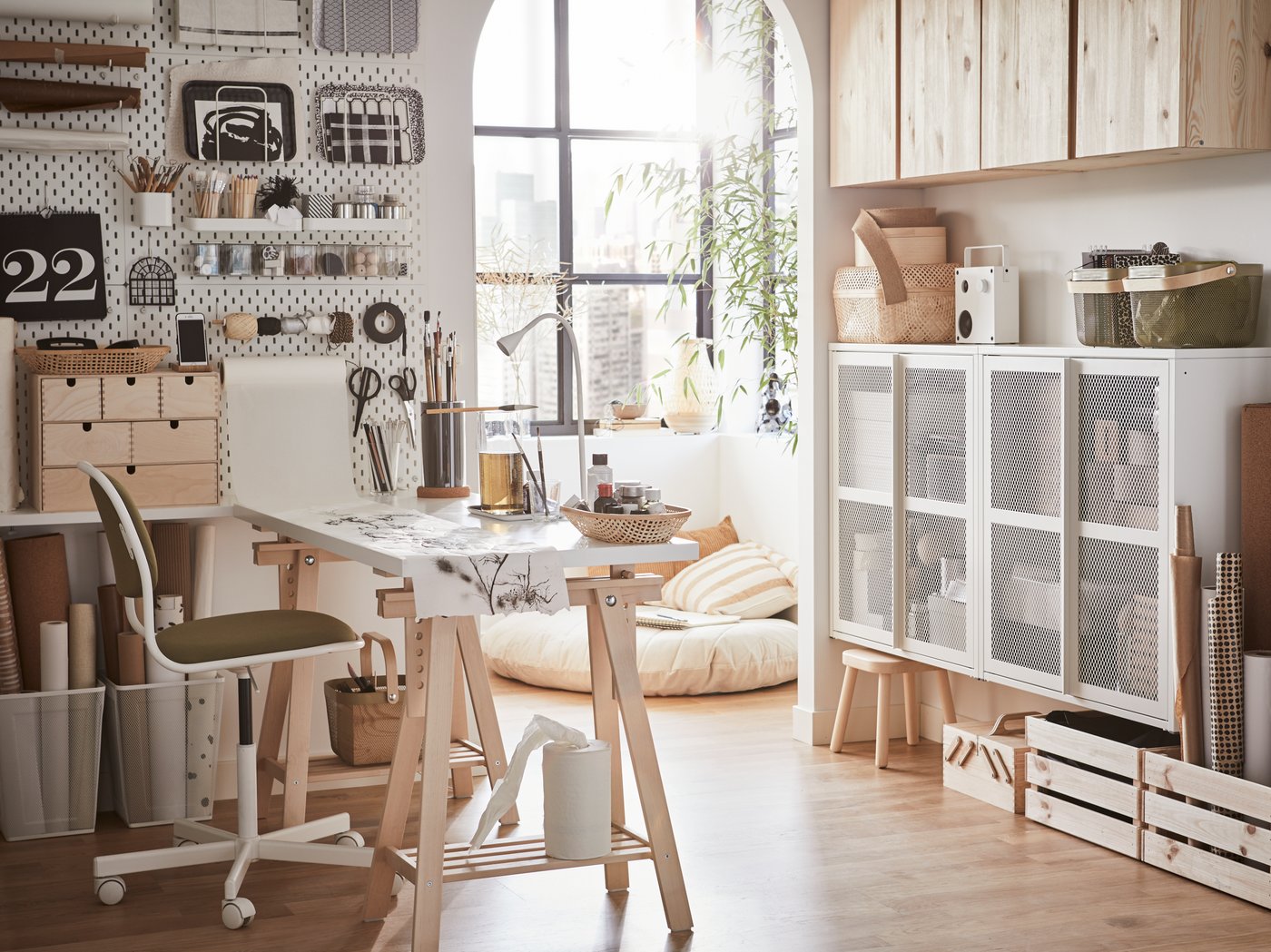 Es ist ein helles Homeoffice mit einem weissen Schreibtisch, einem weiss-gelben Bürostuhl und weissen Lochplatten an der Wand zu sehen.