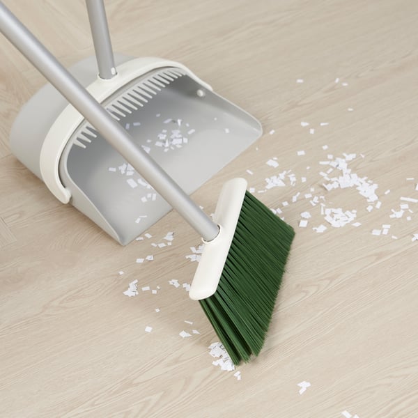 Ein PEPPRIG Kehrset kehrt weiße Papierschnipsel weg.