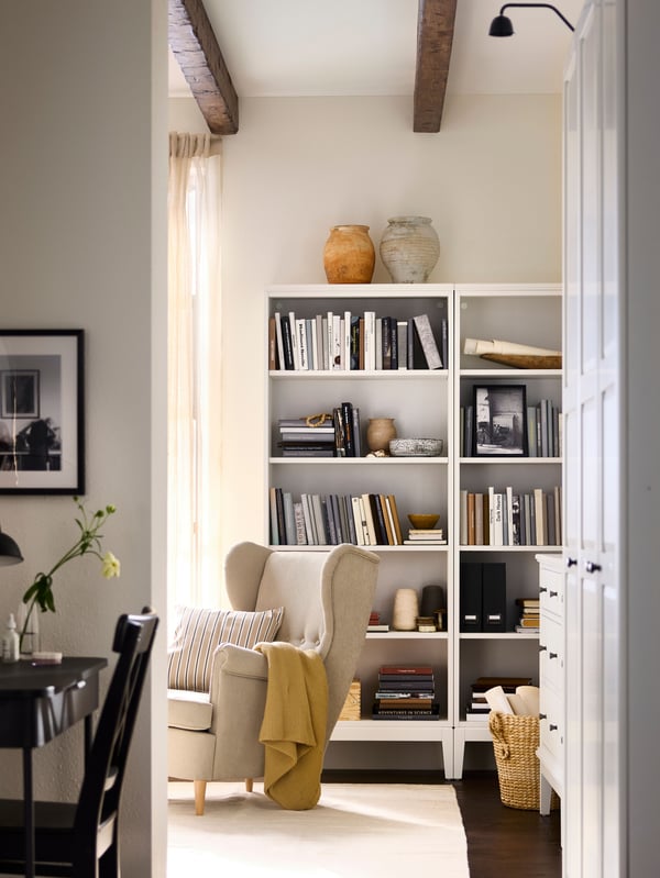 Pathway into bedroom with GRÅFJÄLLET dressing table to the left, wardrobes at right and a bookcase plus armchair further in.
