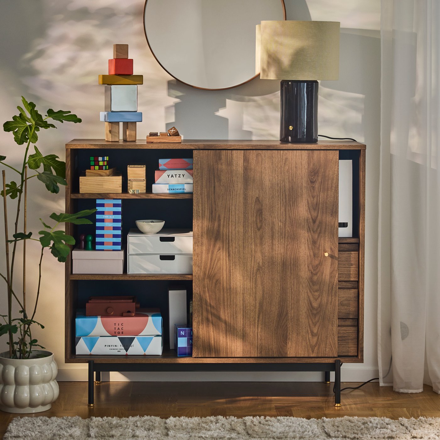 A RÅDMANSÖ cabinet keeps board games and boxes organised behind sliding doors and on open shelves.
