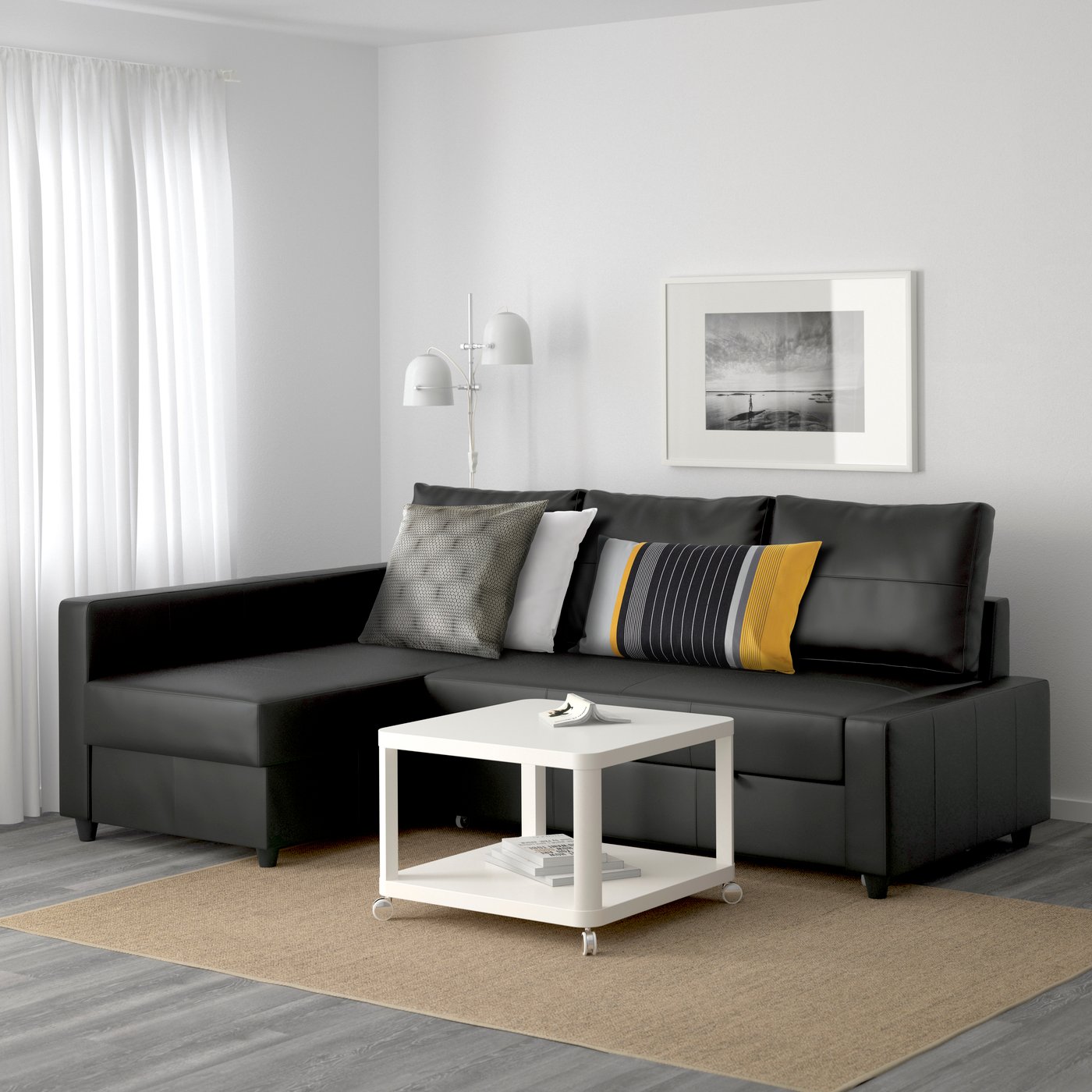 A black FRIHETEN sofa bed in a living room with a white coffee table.