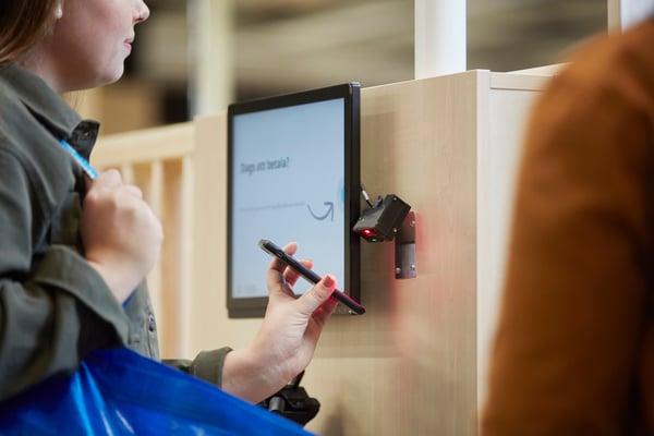 A person using the IKEA App on their mobile phone at the check-out.