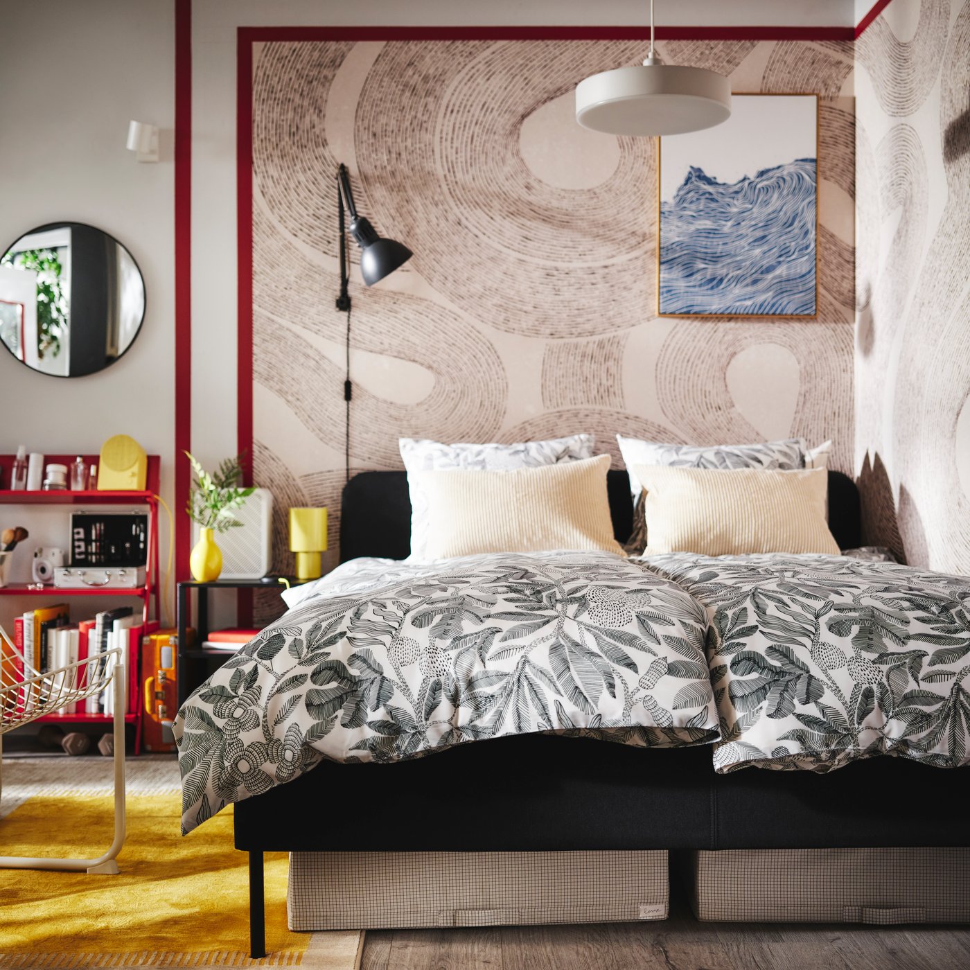 A dark grey SLATTUM upholstered bed in the corner of a bedroom with two duvets covered in BROKDRACENA bed linen on it.