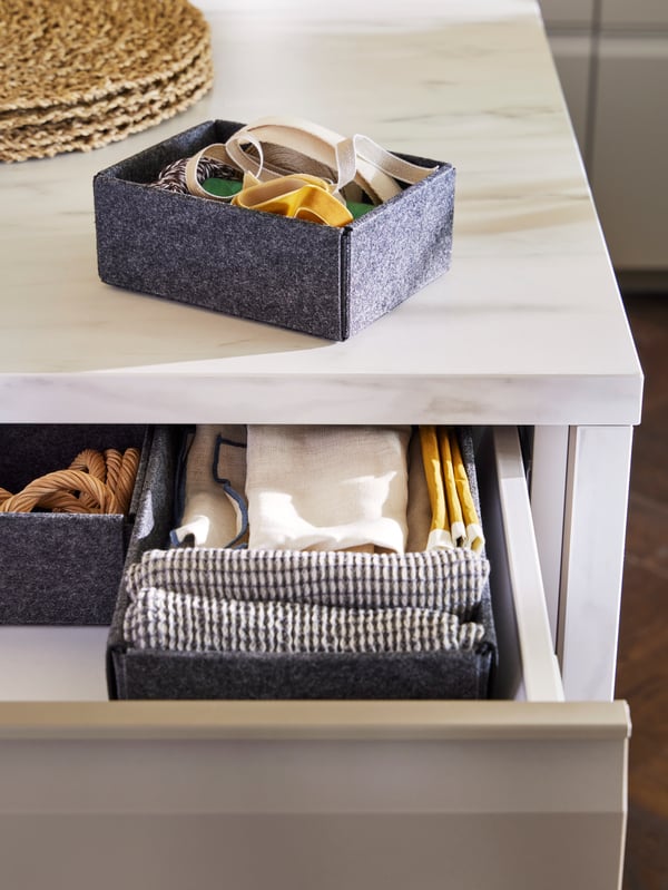 MARIATHERESE dishcloths and other textiles are neatly folded in an UPPDATERA placed inside a pull-out drawer.