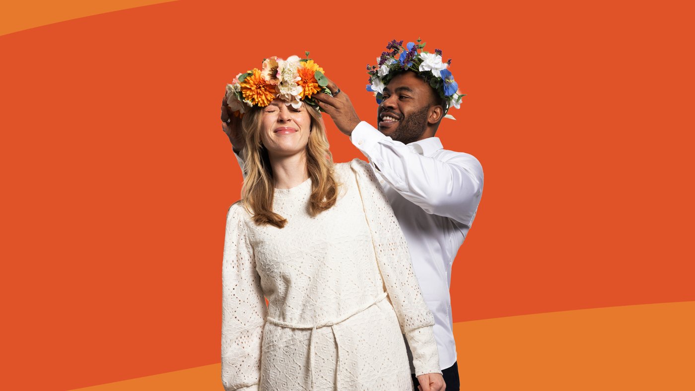 A man with a flower crown on his head is putting a flower crown on a womans head.