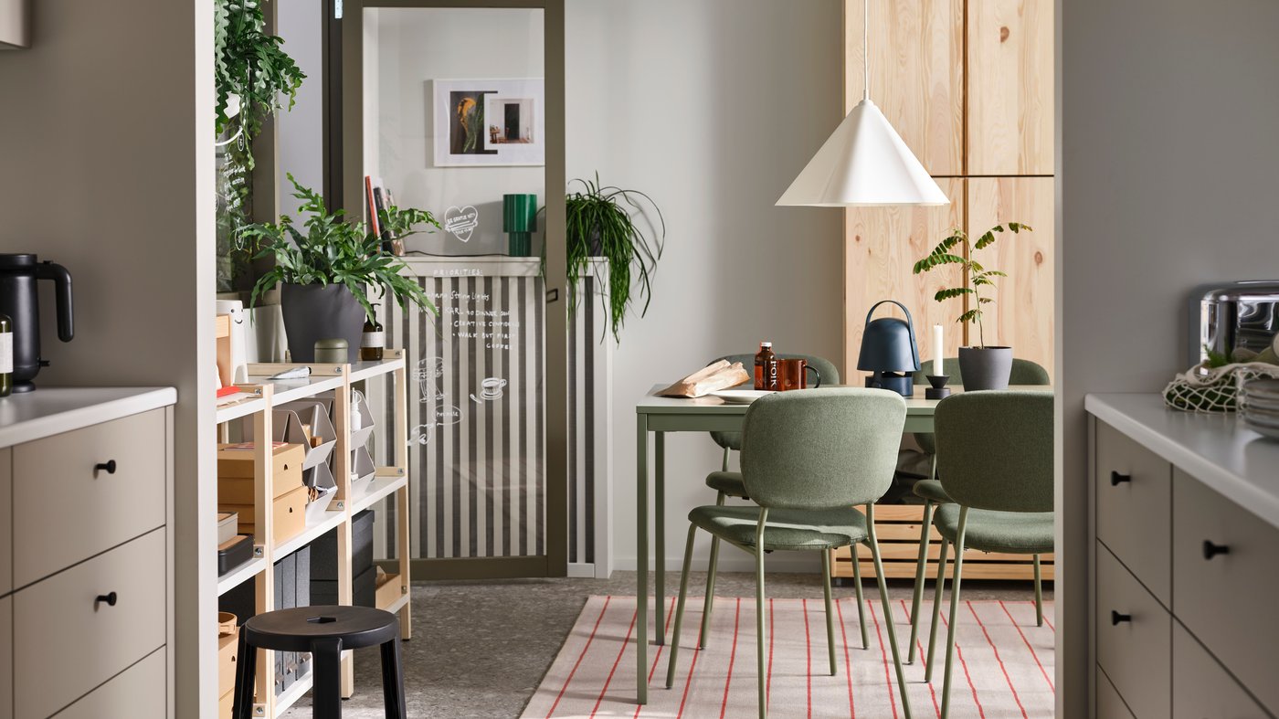 VIHALS chairs stand at a green VIHALS extendable table on a rug underneath a white ZEBRASÄV pendant lamp in a dining room.