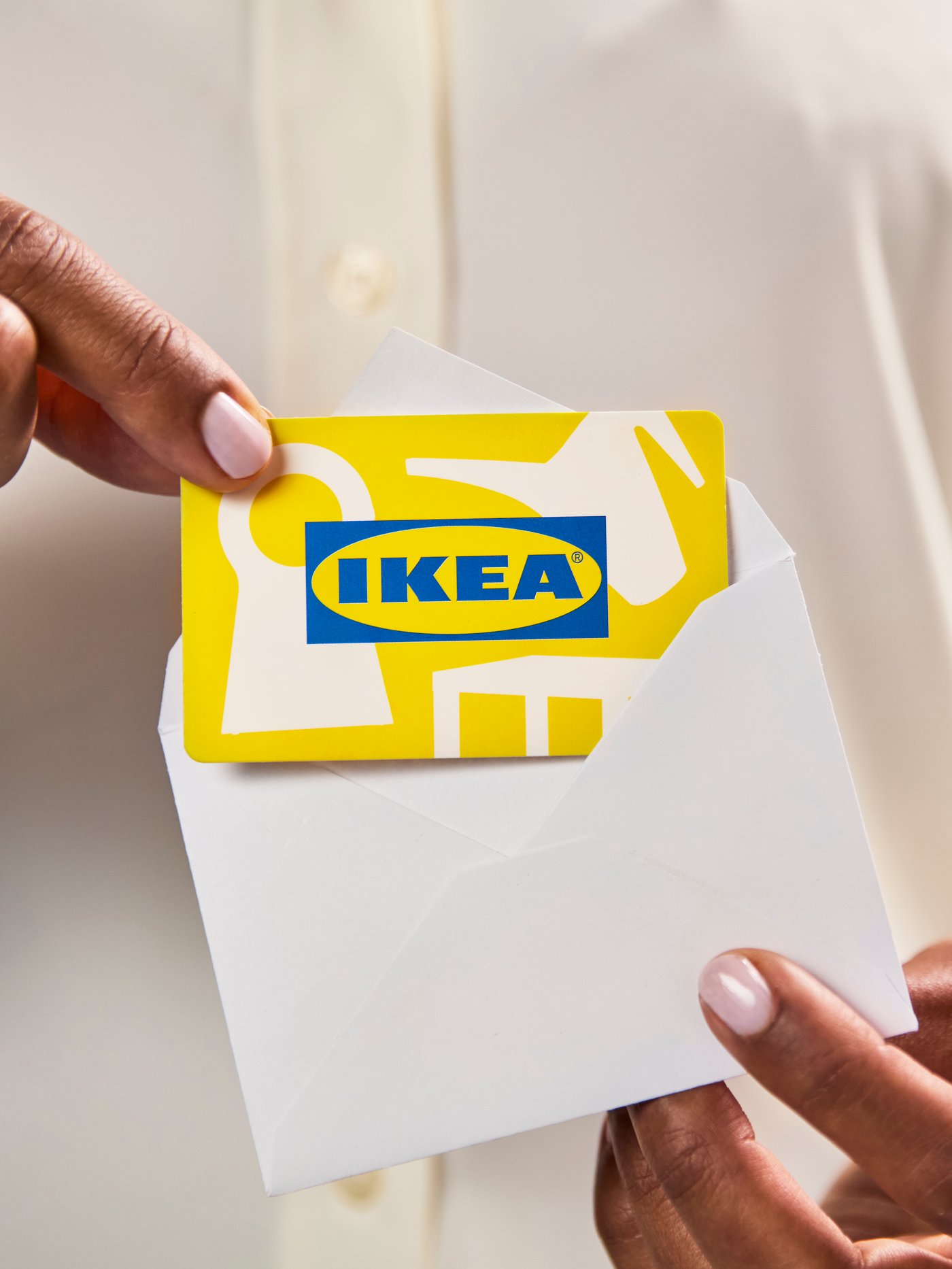 Person som tar frem ett IKEA presentkort ur ett vitt kuvert.