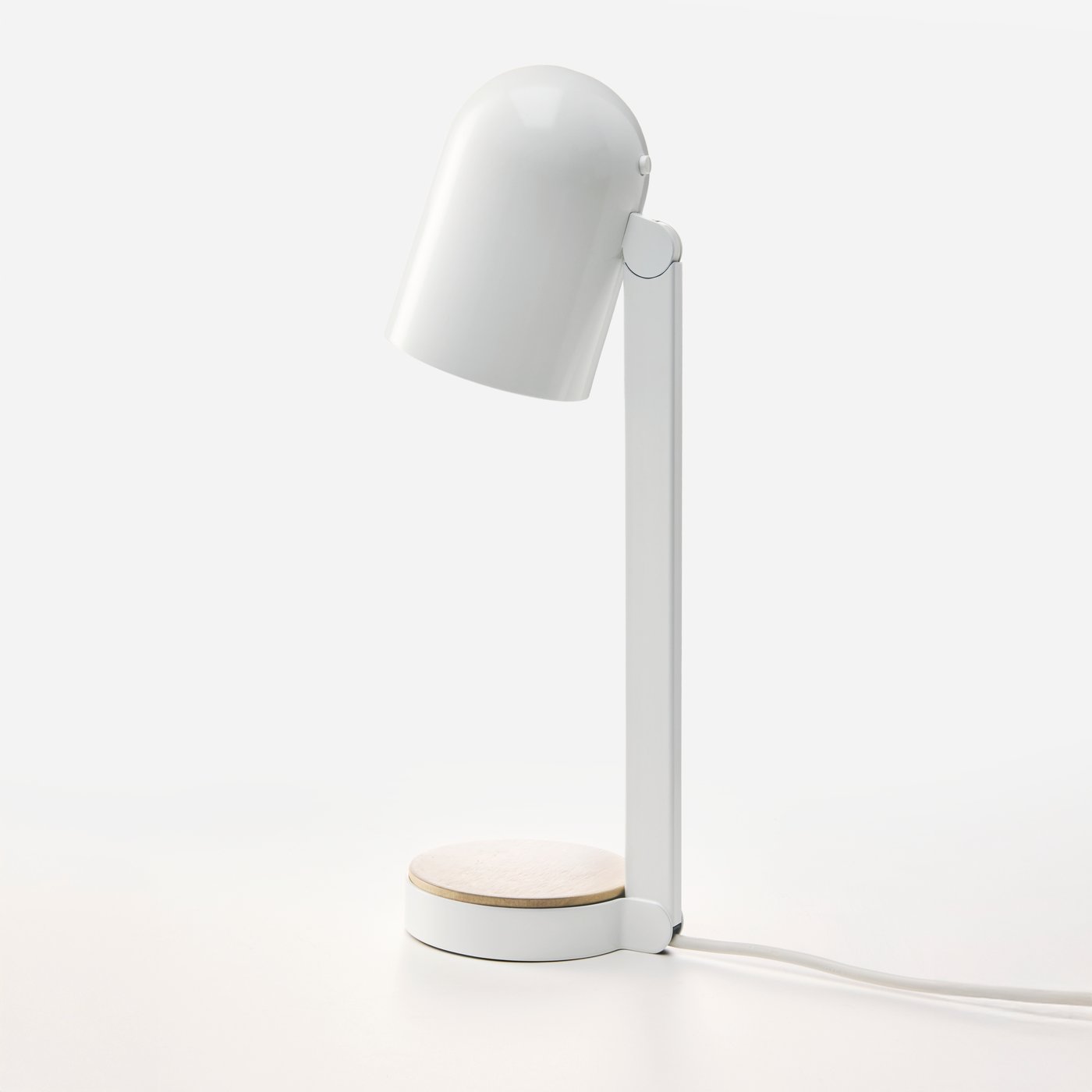 En hvid ENSMÄRKE skrivebordslampe, der står alene på en lys overflade, med lampen rettet næsten lige ned.